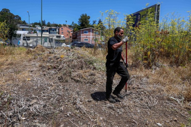 Community member Rafa Rivera cleans up a vacant lot at the corner of MacArthur Boulevard and 83rd Avenue in Oakland, Calif., on Thursday, July 23, 2026. The approximately 15,000-square-foot lot was transferred to the Black Cultural Zone Community Development Commission by Alameda County for $10. (Ray Chavez/Bay Area News Group)