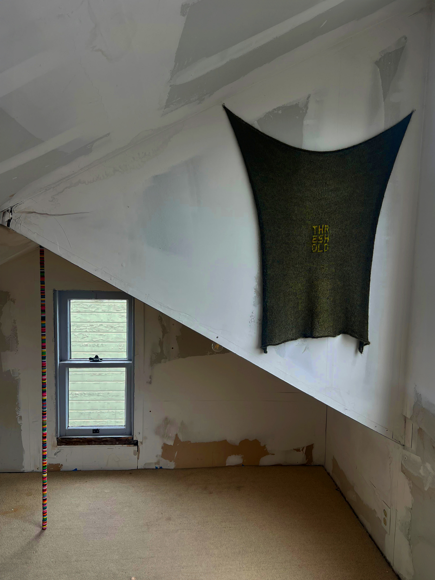 attic space with hanging textile and skinny sculpture
