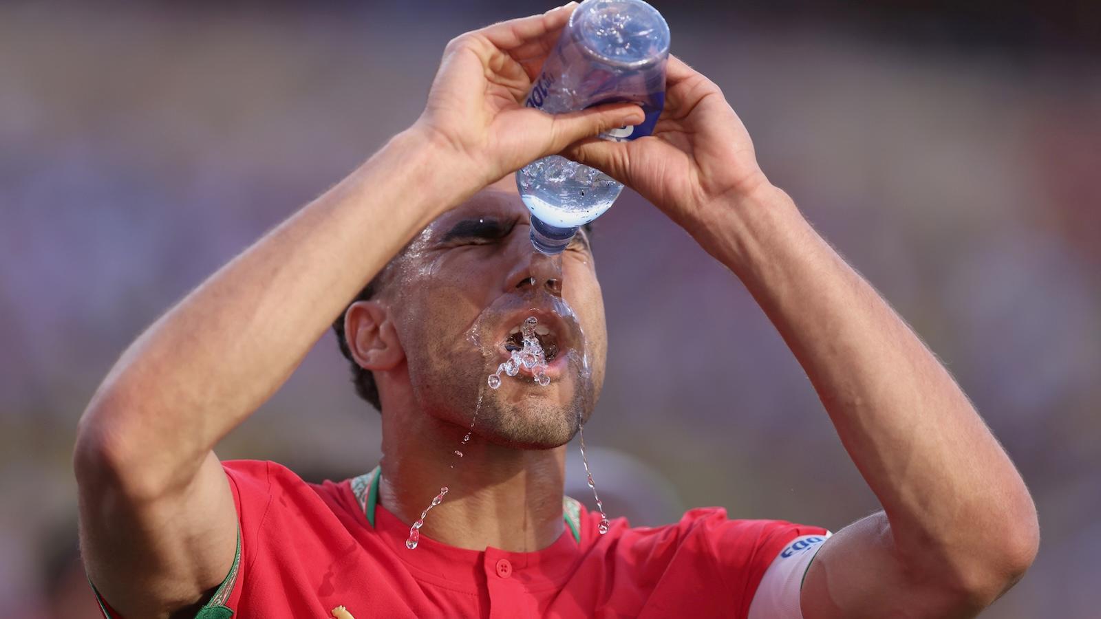 A soccer player douses his face with the bottle of water during a World Cup match.