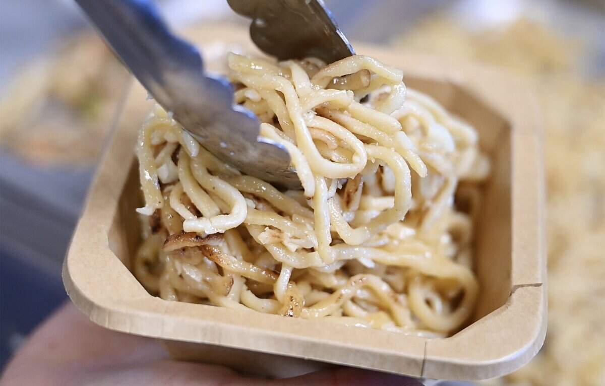 Davanh Phayarath-Khamsone fills a to-go box with garlic noodles from her new Cajun-inspired Asian restaurant Sticky Chix Tuesday, July 28, 2026 in downtown Fresno.