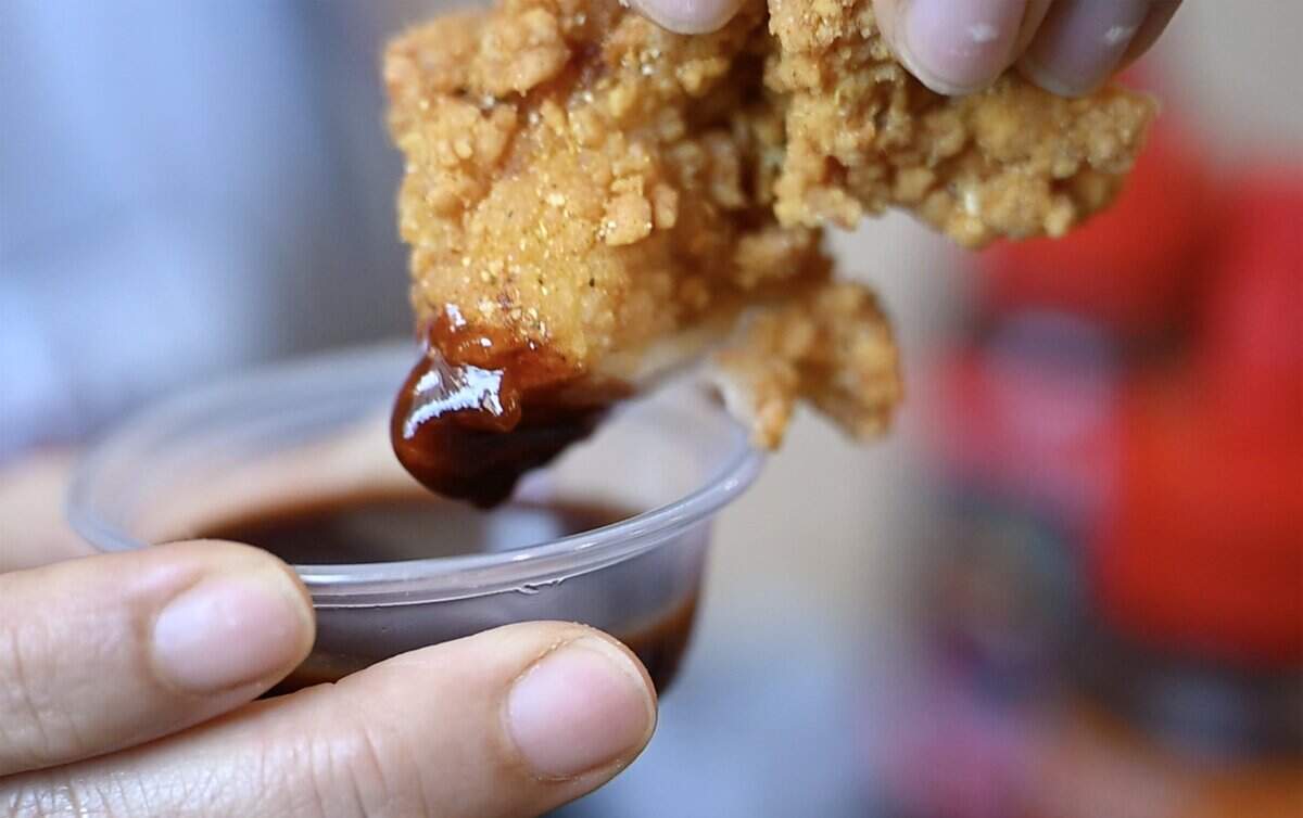 Davanh Phayarath-Khamsone says the fried chicken at her new Cajun-inspired Asian restaurant Sticky Chix has been very popular, as she dips a piece into one of her two new sriracha sauces Tuesday, July 28, 2026 in downtown Fresno.