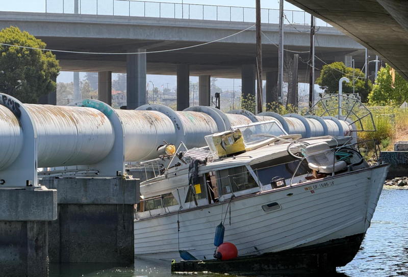 An abandoned boat wedged threatens a pipeline as the tide rises.