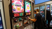A woman seen filling a cup from a Slurpee machine at a 7-Eleven store