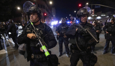 Police in riot gear stand guard.
