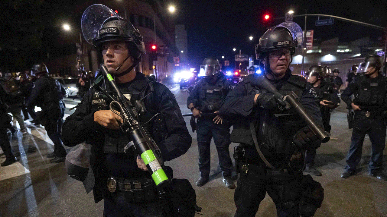 Police in riot gear stand guard.