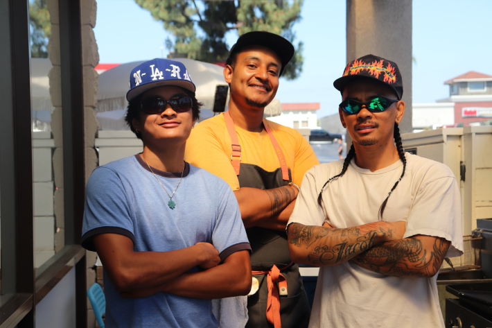three young men posing together in tee shirts and caps