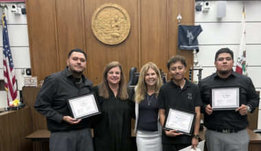 Judge and professor pose with three graduates in courthouse