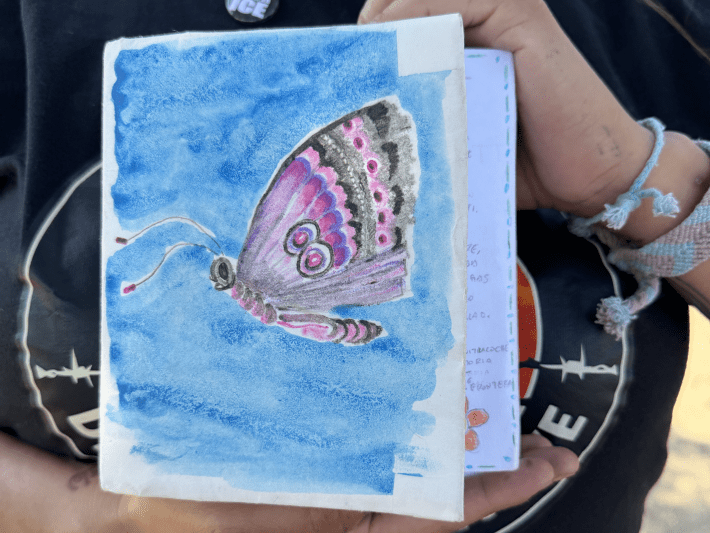 a woman holds a hand-painted card with a butterfly