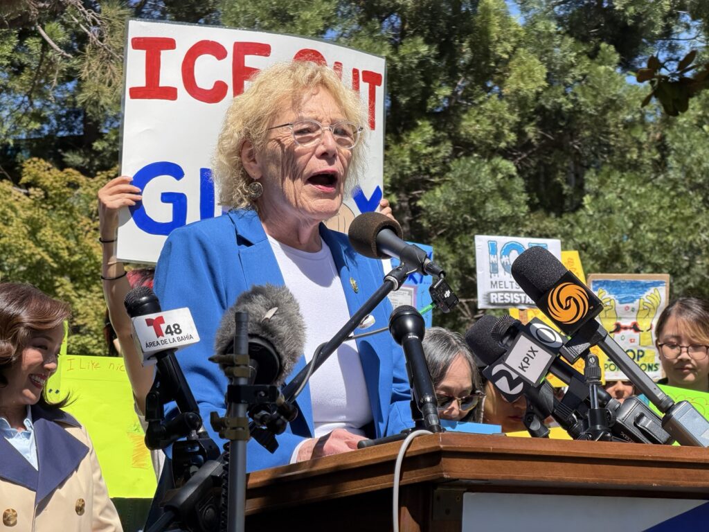 A woman stands behind a podium.