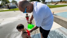 Tyler Downing fills his son's water toy, Saturday, at the Pepper Park splash pad, National City, Calif., July 25, 2026.