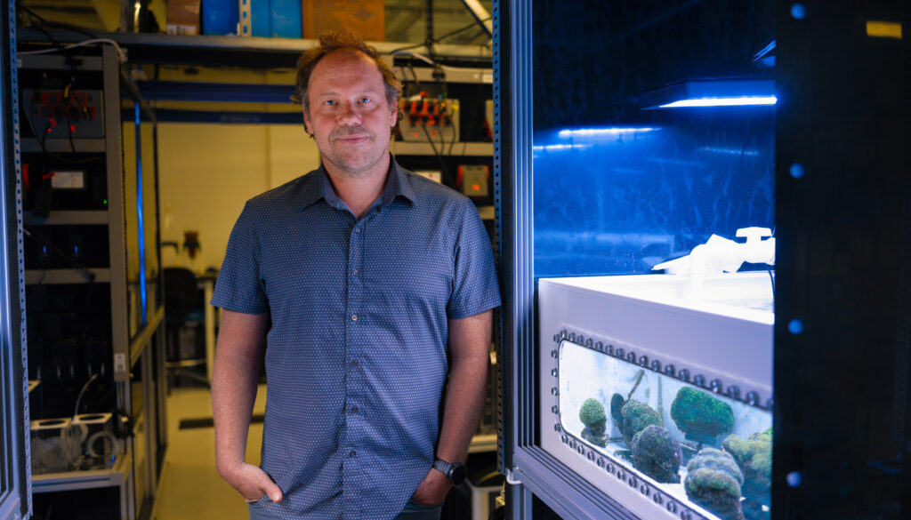 a man standing next to a tank of coral