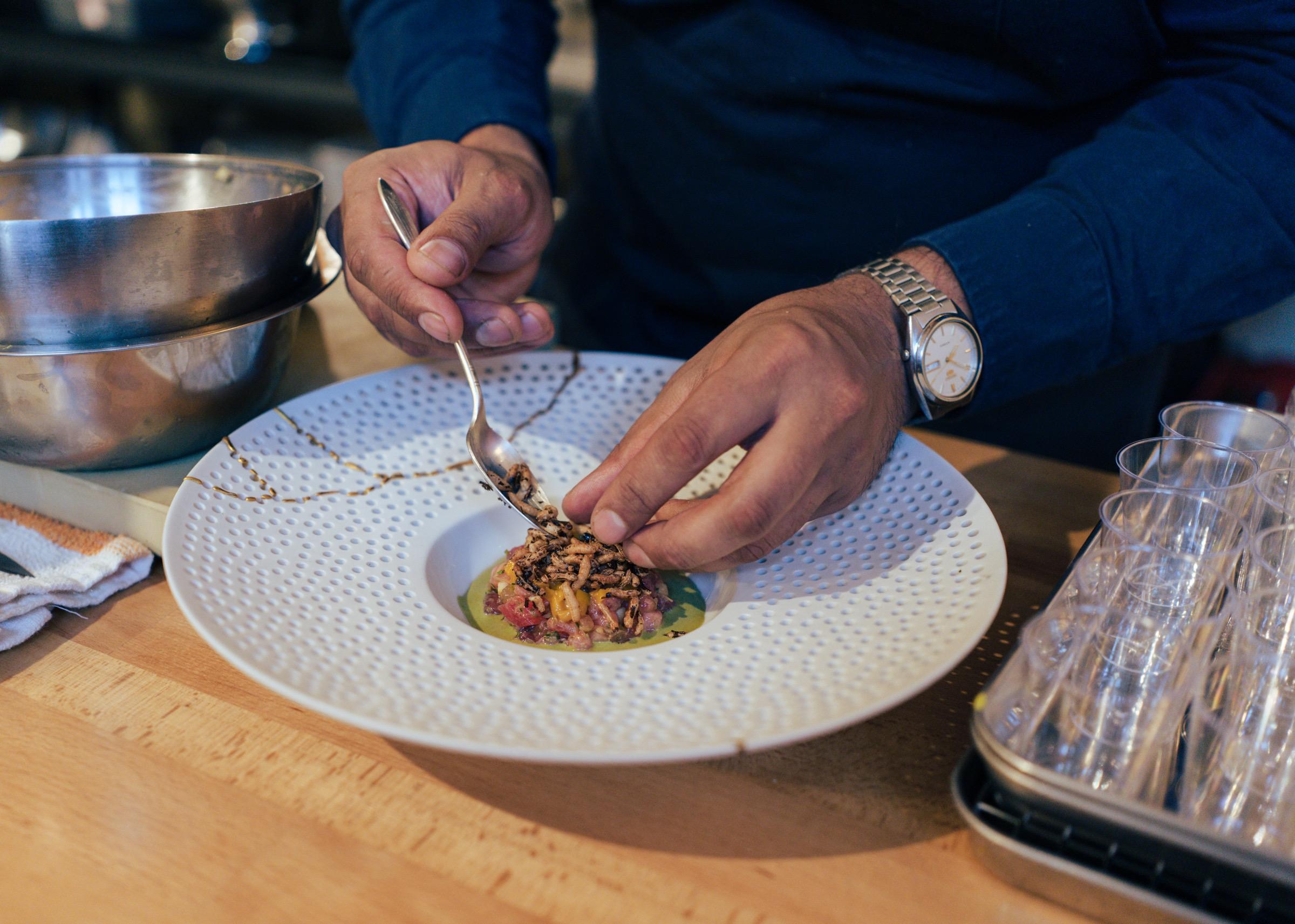 A pair of hands plate a tuna dish with puffed rice from the pop-up Kedar, from chef Kedar Shenoy, in San Francisco.