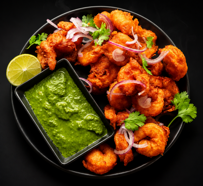 Koliwada-style fish at Golden Tadka next to a rectangular dish of mint chutney and a lemon slice