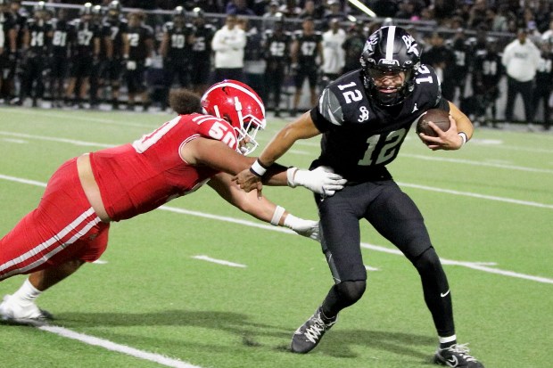 St. John Bosco quarterback Koa Malau'ulu evades an attempted tackle by Mater Dei's Montana Toilolo in Trinity League action at St. John Bosco High School in Bellflower on Friday, Oct. 31, 2025. (Photo by Howard Freshman, Contributing Photographer)