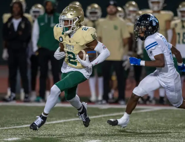 Long Beach Poly's Juju Johnson (2) gets past Jordan's Kymani Hill (3) and heads for the end zone during the Moore League football season opener between Long Beach Poly and Long Beach Jordan at Veterans Stadium, Friday, Sept. 20, 2024. (Photo by Michael Goulding, Contributing Photographer)