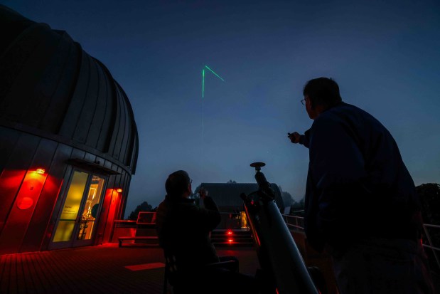 Raymond Howard, left, outreach coordinator for the Eastbay Astronomical Society, and Gerald McKeegan, volunteer and adjunct astronomer, use a laser pointer to show Jupiter to visitors by Howard's telescope at the Chabot Space & Science Center in Oakland, Calif., Friday, May 8, 2026. (Ray Chavez/Bay Area News Group)