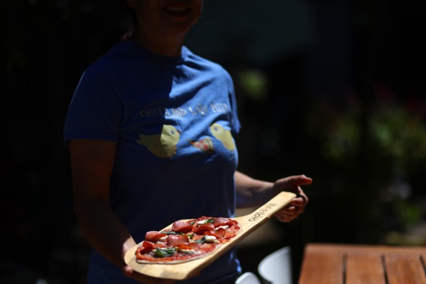 Chef Kellie Joe with a pizza on a wood board in the backyard of her home on Thursday, May 14, 2026, in Pleasant Hill, Calif. Joe holds private pizza parties in her backyard space. (Aric Crabb/Bay Area News Group)