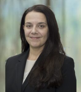 A headshot photo of Mary Hoopes smiling with dark hair while wearing a dark suit jacket.