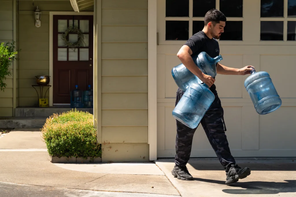 A man carrying water jugs outside a house in Mountain View, California