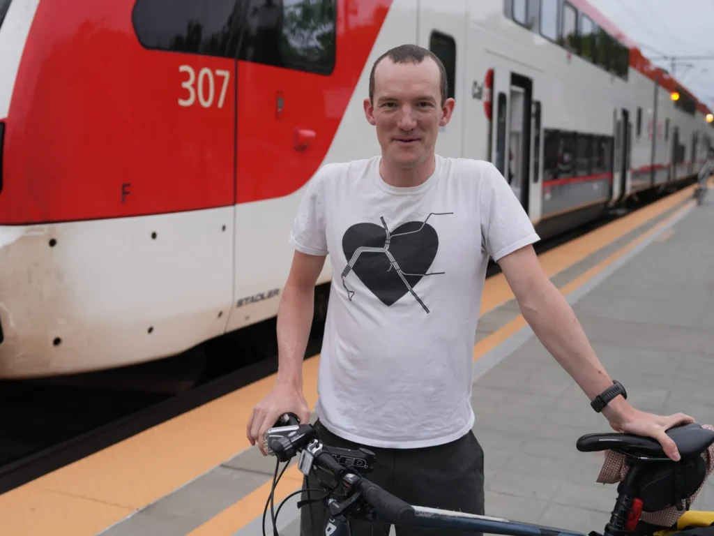 A man stands with a bike in front of a train at a station in Mountain View, California