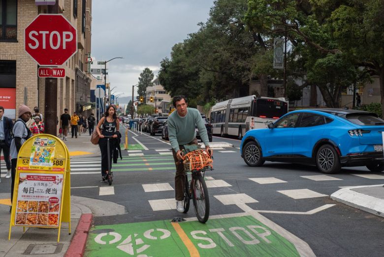 People ride bikes along a wide two-way bike lane that is painted green.