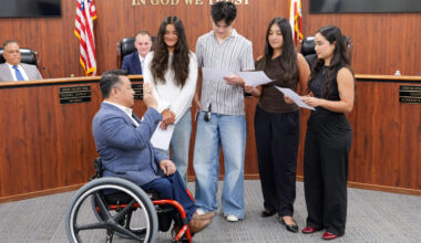 Dr. Stefan Bean raises his right hand while his four children administer the oath of office during an Orange County Board of Education meeting.