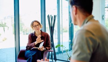 Female professional giving guidance and support to a man during a therapy session in a modern office setup