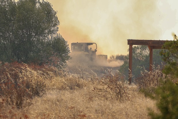 A Cal Fire firefighter used a bulldozer to create a firebreak near homes in Ramona during the Creelman fire on Wednesday. (Stephanie Ogilvie)