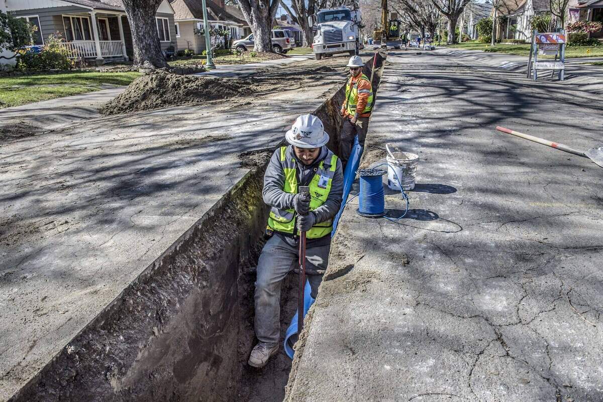 Workers install a pipe on Robertson Way in Sacramento as part of a water meter project in 2018.