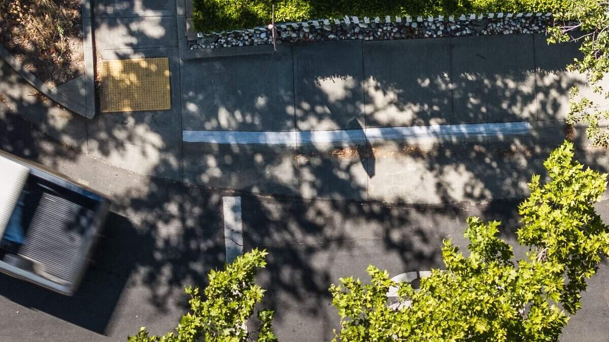 A drone view shows a sidewalk painted gray by the city in Curtis Park on Friday, July 17, 2026. The city painted over a 20-foot red stripe on the sidewalk.