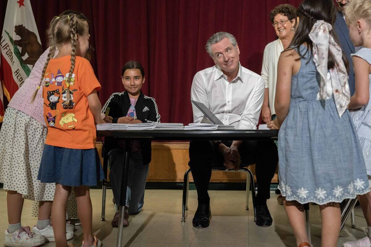 Gov. Gavin Newsom makes a face before signing Assembly Bill 126 as schoolchildren look on at Robert E. Willett Elementary School in Davis on Thursday. The bill will increase funding for special education across the state.
