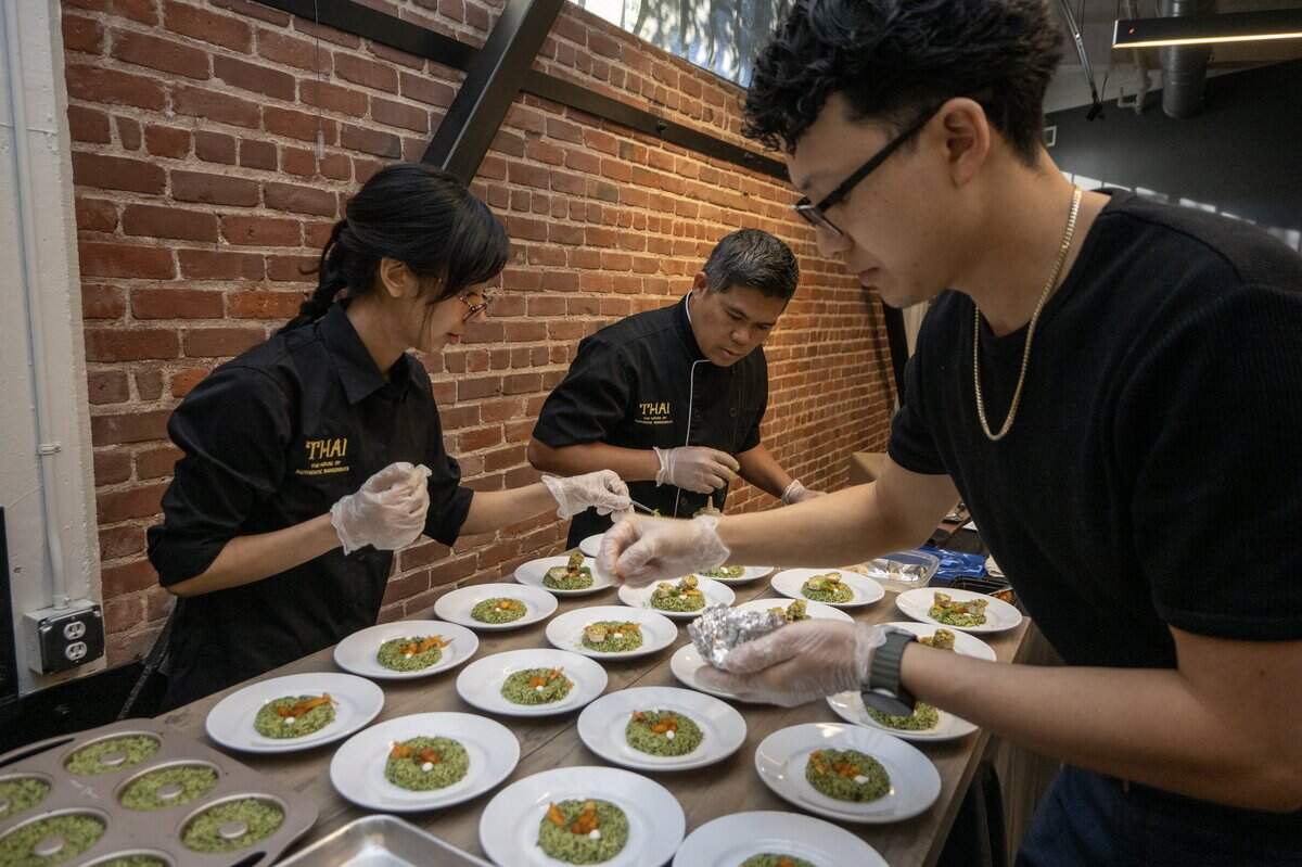 Thai chef Wong Jankhuen, center, prepares his entry of pesto chicken and basil pesto rice with grilled chicken and a sweet pepper-peach red curry sauce with assistance from Dorien Rodriguez, left, and Stephanie Tran during the Savor East Sac Chef's Challenge on Friday, July 24, 2026, in Sacramento, Calif.