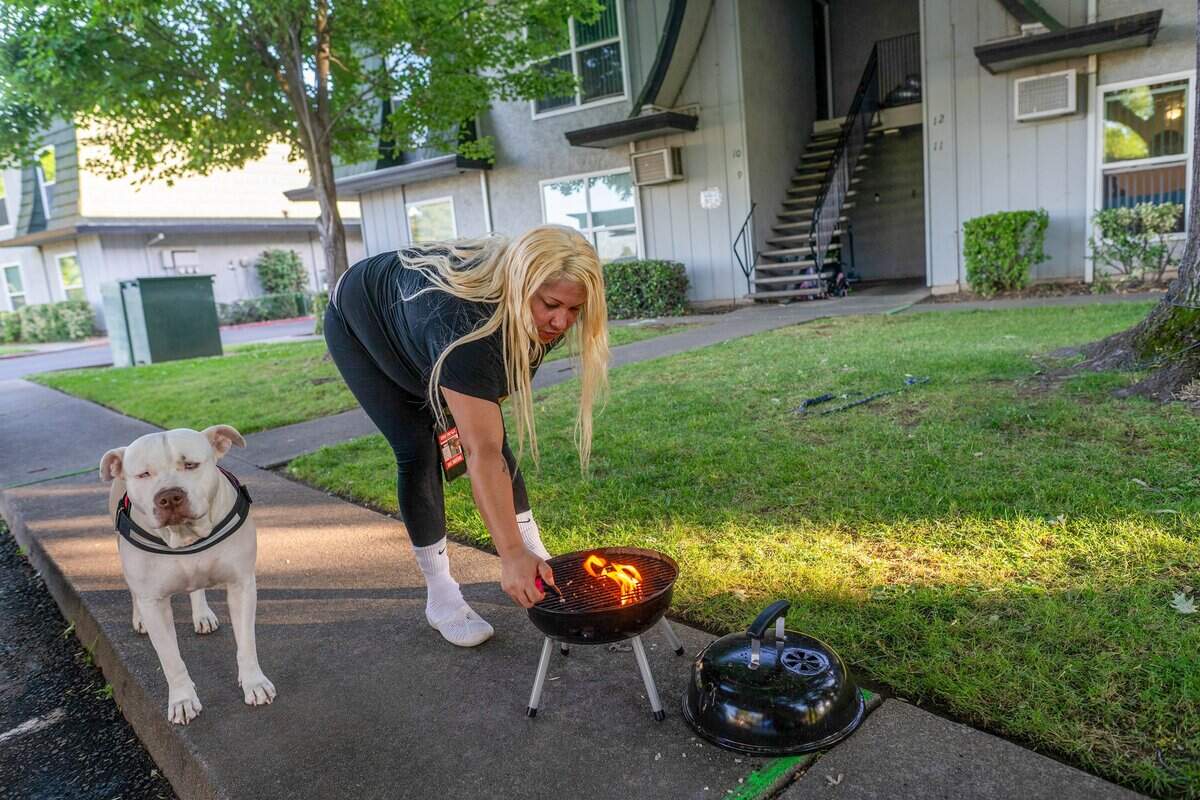 Jocelyn Wright, 40, prepares her grill to cook dinner with her dog, Blue, outside her apartment in Rancho Cordova on June 9. Turning Point paid her security deposit and first month’s rent, but she said she must attend her mental health appointments to qualify for additional assistance.