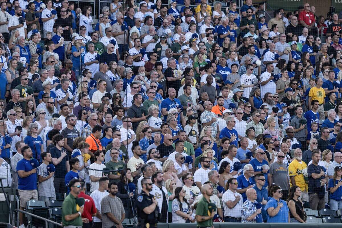 Fans, wearing mostly blue, stand for the national anthem at Sutter Health Park in West Sacramento before a game between the Athletics and the Los Angeles Dodgers on June 29.