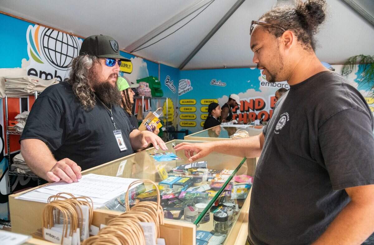 Independent budtender Tyler Sherlock, left, explains purchase options for cannabis products to a customer in the vendor area of the cannabis exhibit at the California State Fair in Sacramento on Tuesday, July 16, 2024. “I want to be part of it just for the historic aspect,” Sherlock said regarding his participation in California’s first state-sanctioned fair permitting on-site cannabis product sales and consumption.