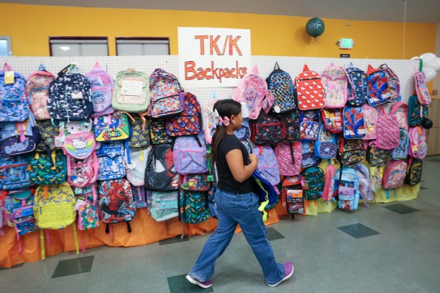 Jayme Nguyen, 8, of San Jose helps place backpacks on the wall while volunteering at Sacred Heart Community Service in San Jose, Calif., on Tuesday, July 28, 2026. (Shae Hammond/Bay Area News Group)