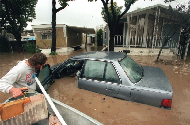 After flooding from a big storm during an El Niño winter, Marcel Zuber checks his neighbor's car in the Golden Wheel Mobile Home Park on Oakland Road in San Jose, Calif. on Feb. 3, 1998. Zuber helped evacuate some of his neighbors in his boat, which he pulled through the flooded park. (Eugene Louie/San Jose Mercury News)