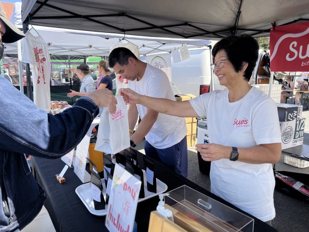 Penny Tom helps a customer while her son Darryl works at the Sue's Bites and Delights booth at San Jose's Japantown Farmers Market on June 14, 2026. (Photo by Grace Hwang Lynch)