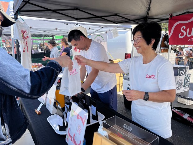 Penny Tom helps a customer while her son Darryl works at the Sue's Bites and Delights booth at San Jose's Japantown Farmers Market on June 14, 2026. (Photo by Grace Hwang Lynch)