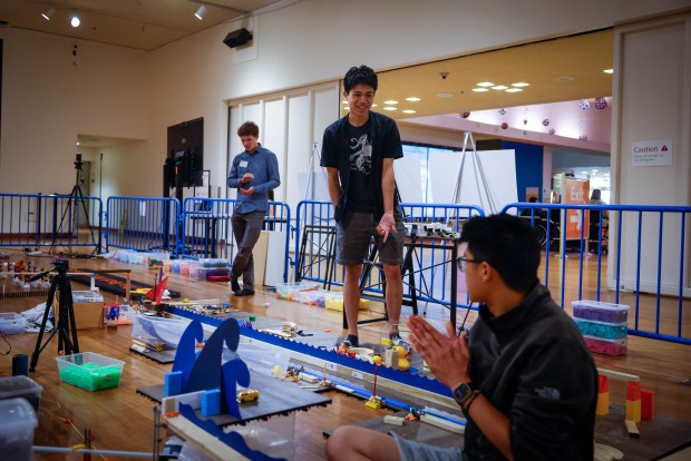 Alex Huang, a transport engineer from San Jose, right, claps after Zane Chattra, of Washington, center, demonstrates a section he was working on for The Tech Topple: The Great Adventure at The Tech Interactive in San Jose, Calif., on Thursday, July 16, 2026. (Shae Hammond/Bay Area News Group)