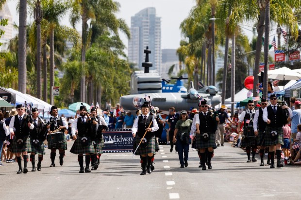 With a USS Midway inflatable in tow, the Cameron Highlanders march during the Independence Day parade at Coronado on Saturday, July 4, 2026. (Kristian Carreon / The San Diego Union-Tribune)