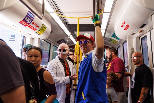San Diego, California - Brendan, right, and Sean Mehaffy, dressed as Ash and Blaine from the cartoon "Pokémon" ride the green line trolley to Comic-Con on Saturday, July 25, 2026. (Kristian Carreon / The San Diego Union-Tribune)