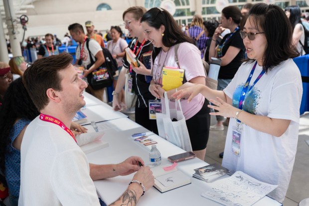 San Diego, CA - Chip Pons signs a book for Jessica Liou upstairs in the autograph zone during Comic-Con on Saturday, July 25, 2026, in San Diego, CA. (Luke Johnson / The San Diego Union-Tribune)