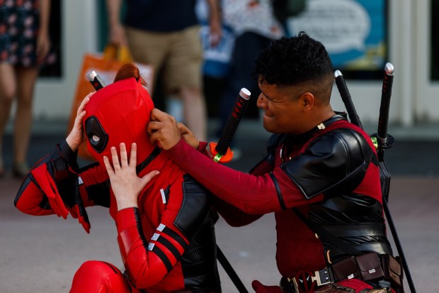 San Diego, California - Joram Leon helps Floral Lara put on her Deadpool mask during Comic-Con on Saturday, July 25, 2026. (Kristian Carreon / The San Diego Union-Tribune)