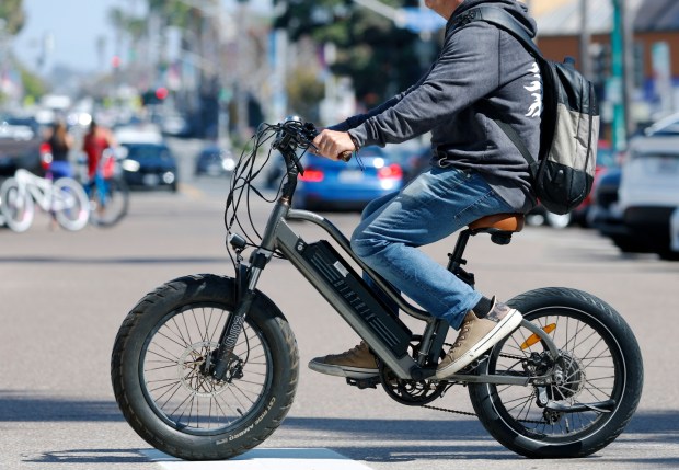 A person rides an e-bike in Pacific Beach in March. (K.C. Alfred / The San Diego Union-Tribune)