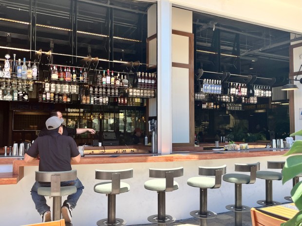San Diego's new Global Fork Food Hall in Little Italy features a large indoor-outdoor bar that features movable shelves of liquor bottles. (Lori Weisberg / The San Diego Union-Tribune)