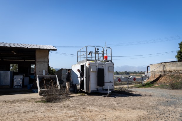 Scientists from Scripps Ben Rico, 28, left, and Tobie Bloom, 24, visit a trailer that has a hydrogen sulfide monitor to pull data on Thursday, April 10, 2025 in San Diego, California. (Ana Ramirez / The San Diego Union-Tribune)