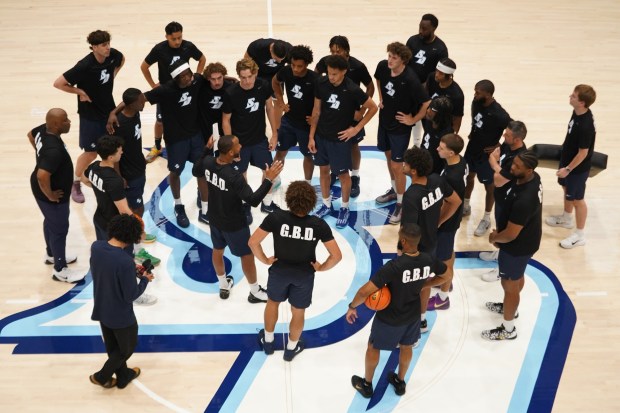 Members of USD's men's basketball team talk with coach JR Blount at midcourt during a recent practice. The Toreros are practicing in T-shirts that read "G.B.D.," short for "Get Better Daily." (USD athletics)