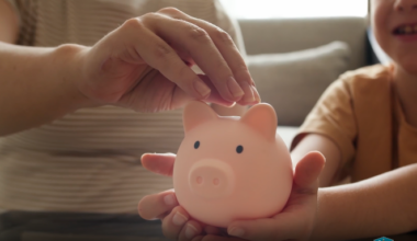 An adult and child place coins into a pink piggy bank, representing college and career savings opportunities available through the CalKIDS program.
