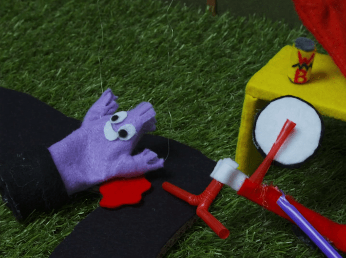 a felt puppet of a tube man next to a miniature bike